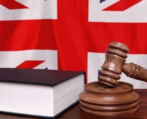Richterhammer und ein Gesetzbuch vor der britischen Flagge