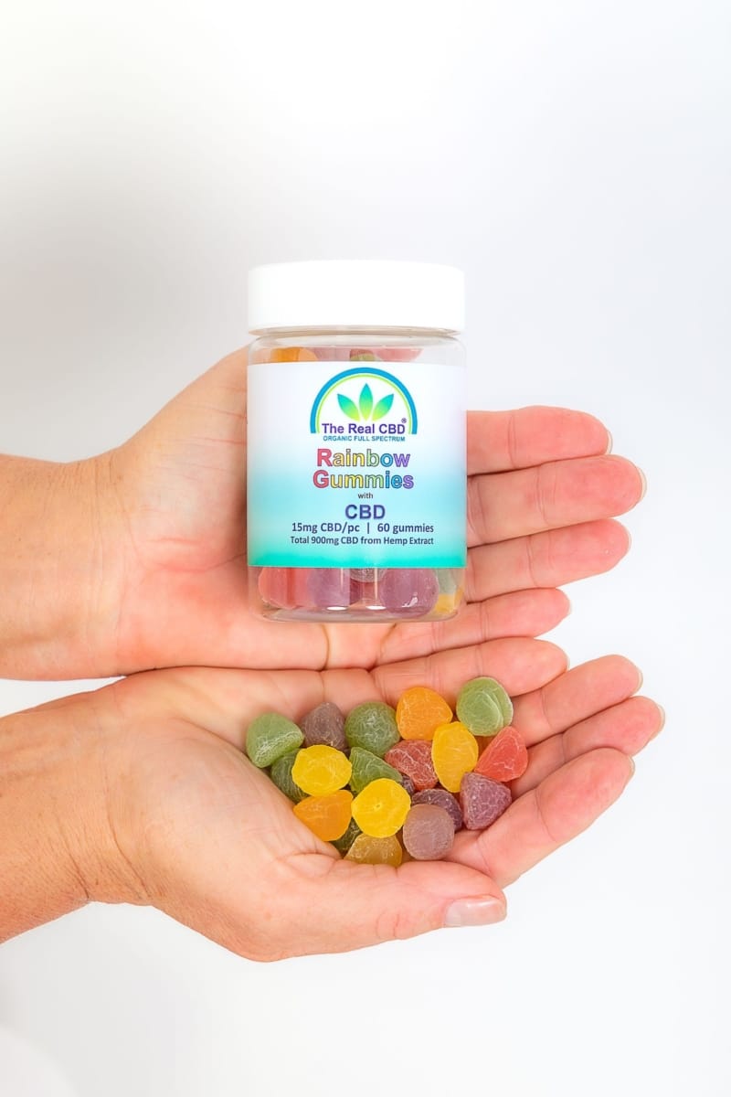 CBD rainbow gummies displayed in open hands - The Real CBD Brand